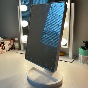 Mini vanity mirror with jewelry storage and tap button.